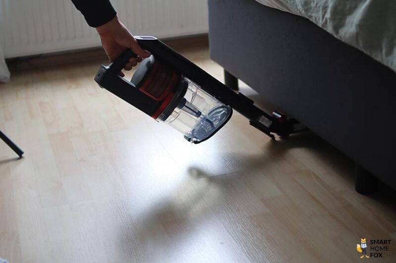 Man sieht den Shark Anti Hair Wrap Flexoloxy bei der Reinigung unter Möbeln.